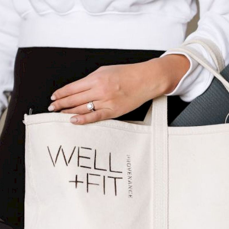 A person is holding a beige tote bag labeled 