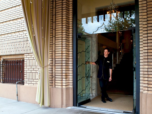 A person standing in the entrance of a hotel with a mat labeled 
