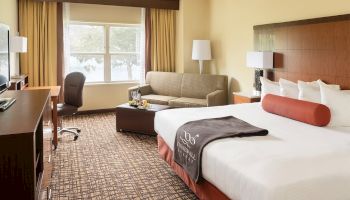 Hotel room with a bed, sofa, desk, and a window.