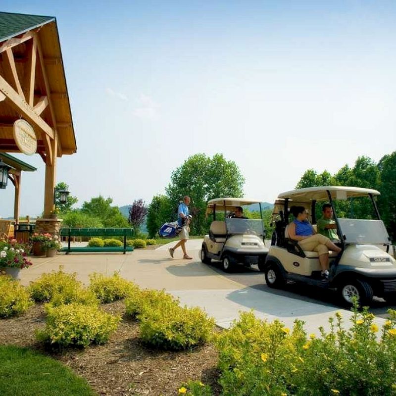 Golf carts parked near a building with people enjoying a sunny day outdoors.